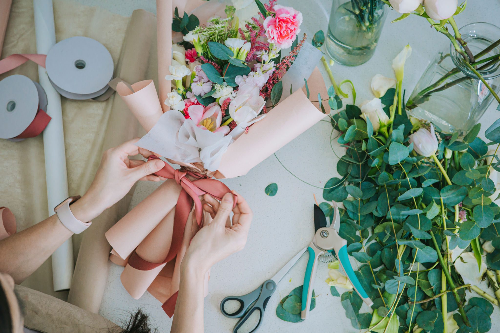 Hands tying ribbon on floral arrangement