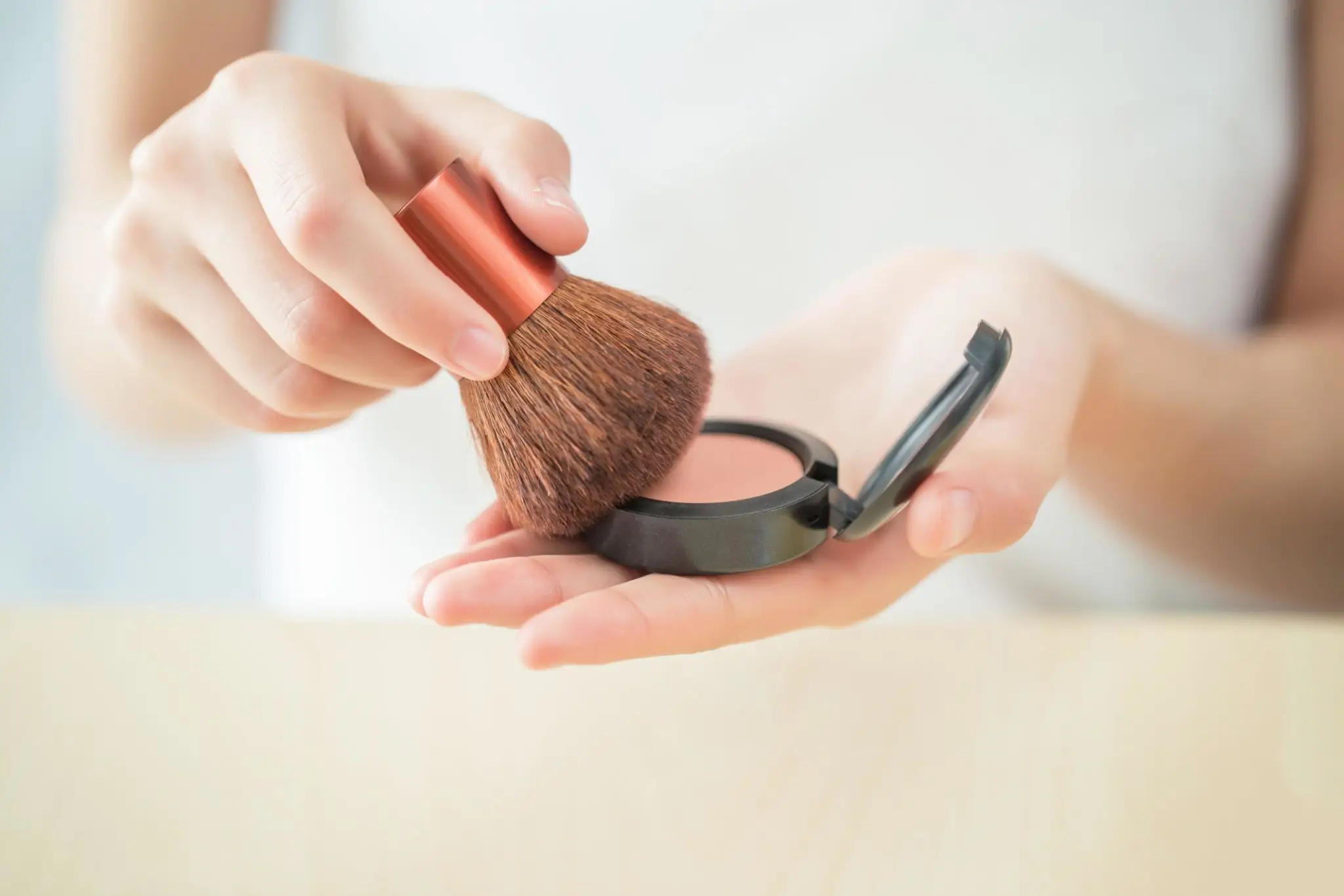 Person using blush compact and brush