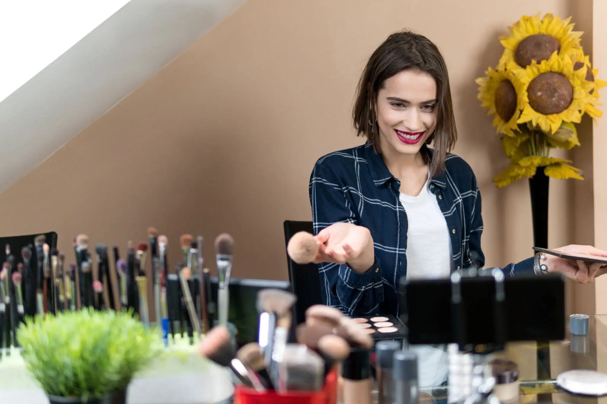 Woman applying makeup with brushes at vanity