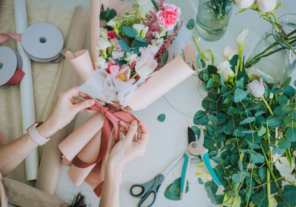 Hands tying ribbon on floral arrangement