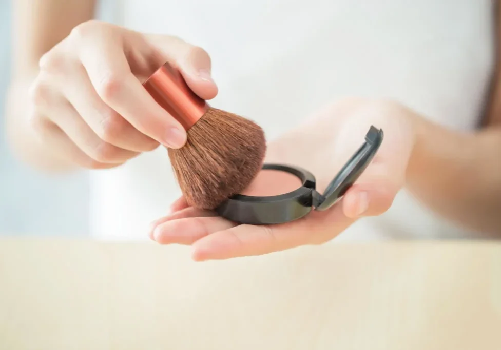 Person using blush compact and brush