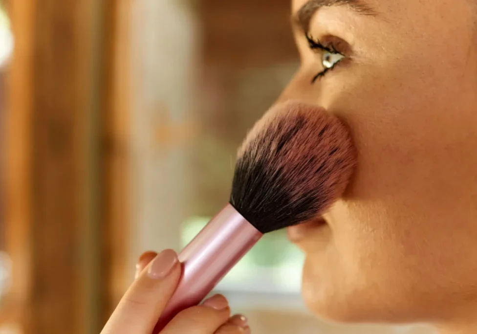 Woman using blush brush on face