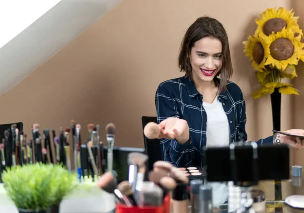 Woman applying makeup with brushes at vanity